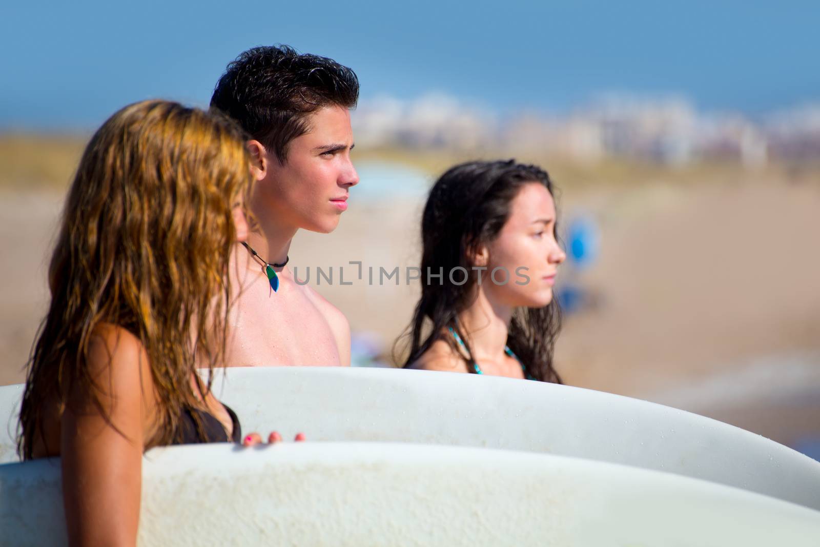 Teenager surfers group happy in beach shore by lunamarina