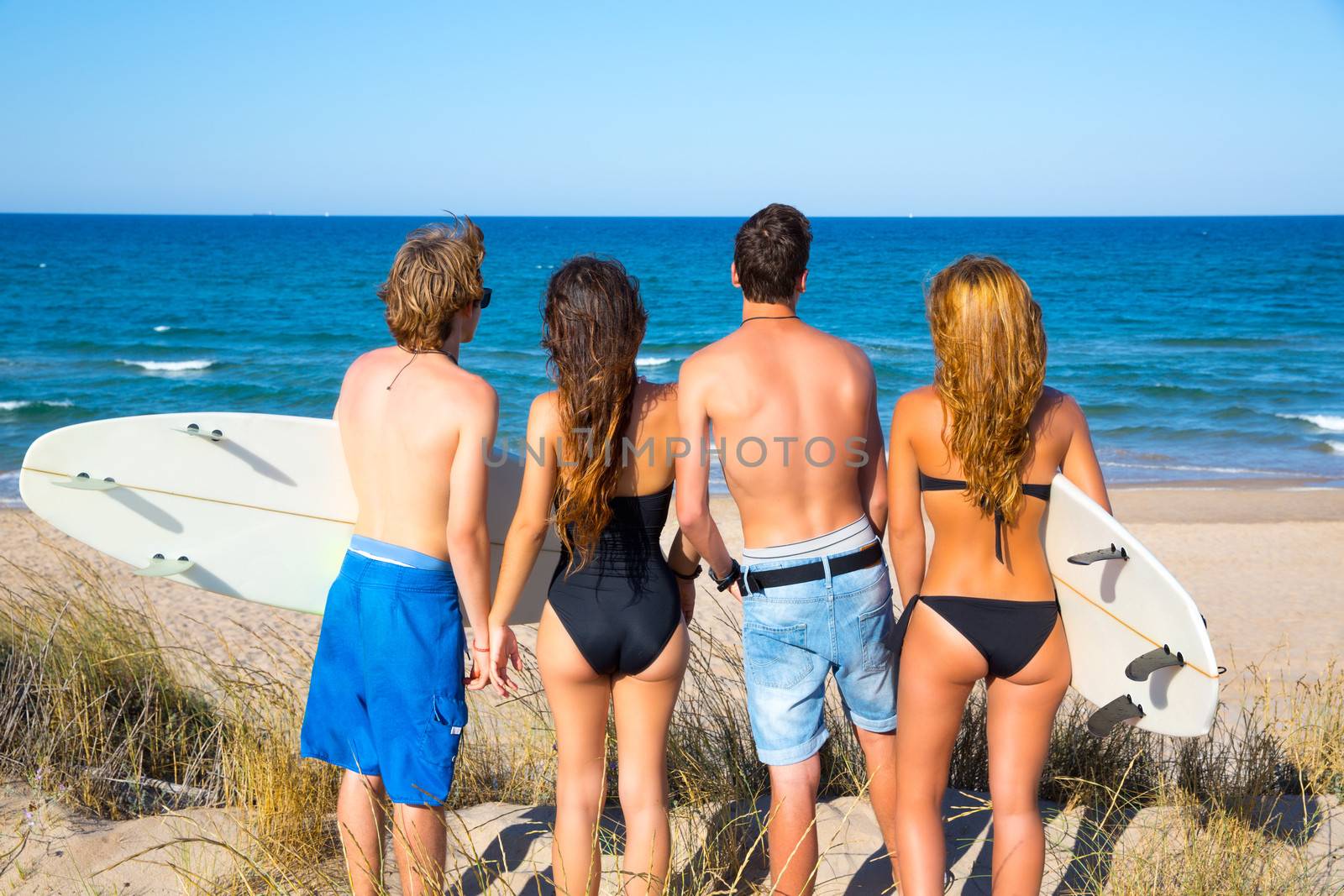 Boys and girls teen surfers rear view looking beach by lunamarina