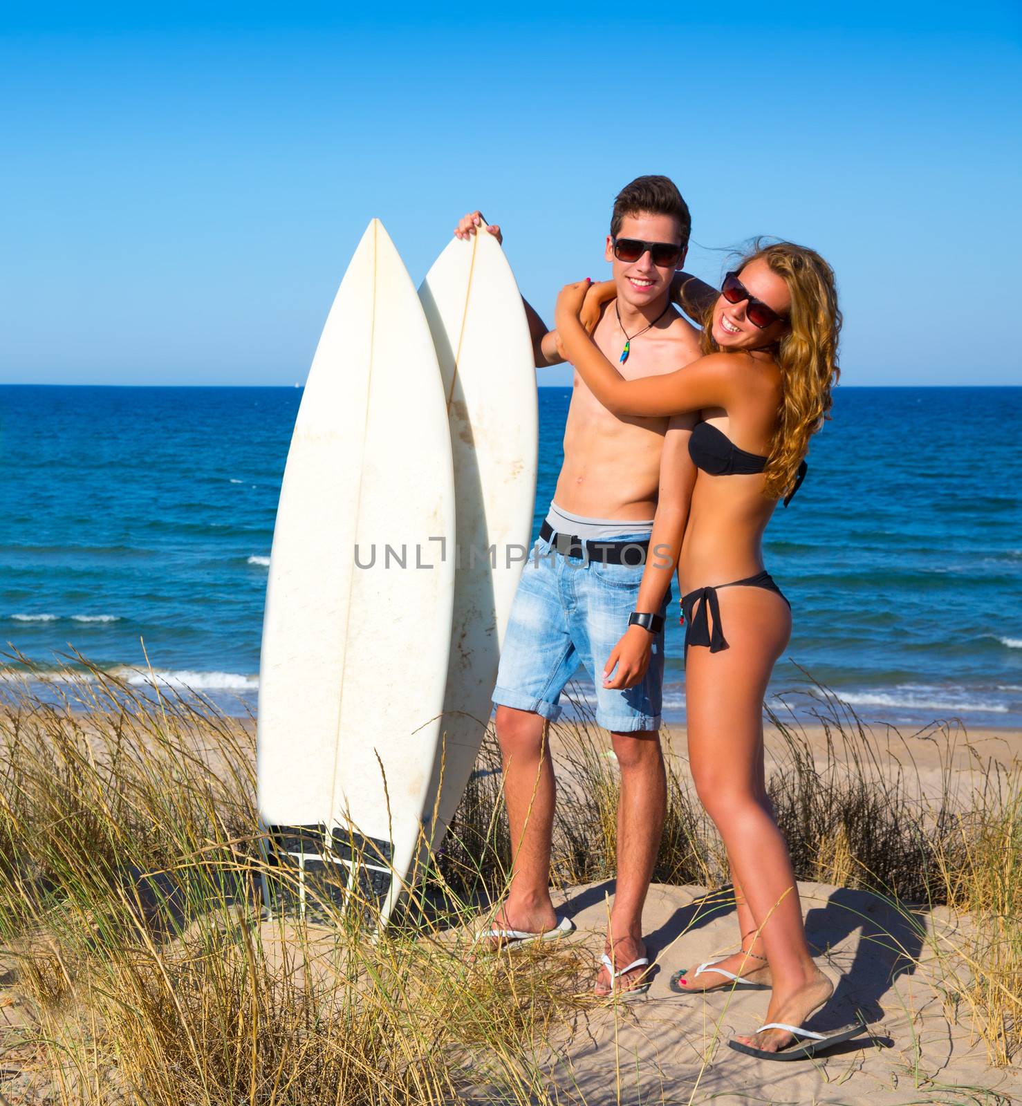 Teen surfers couple hug on the beach by lunamarina