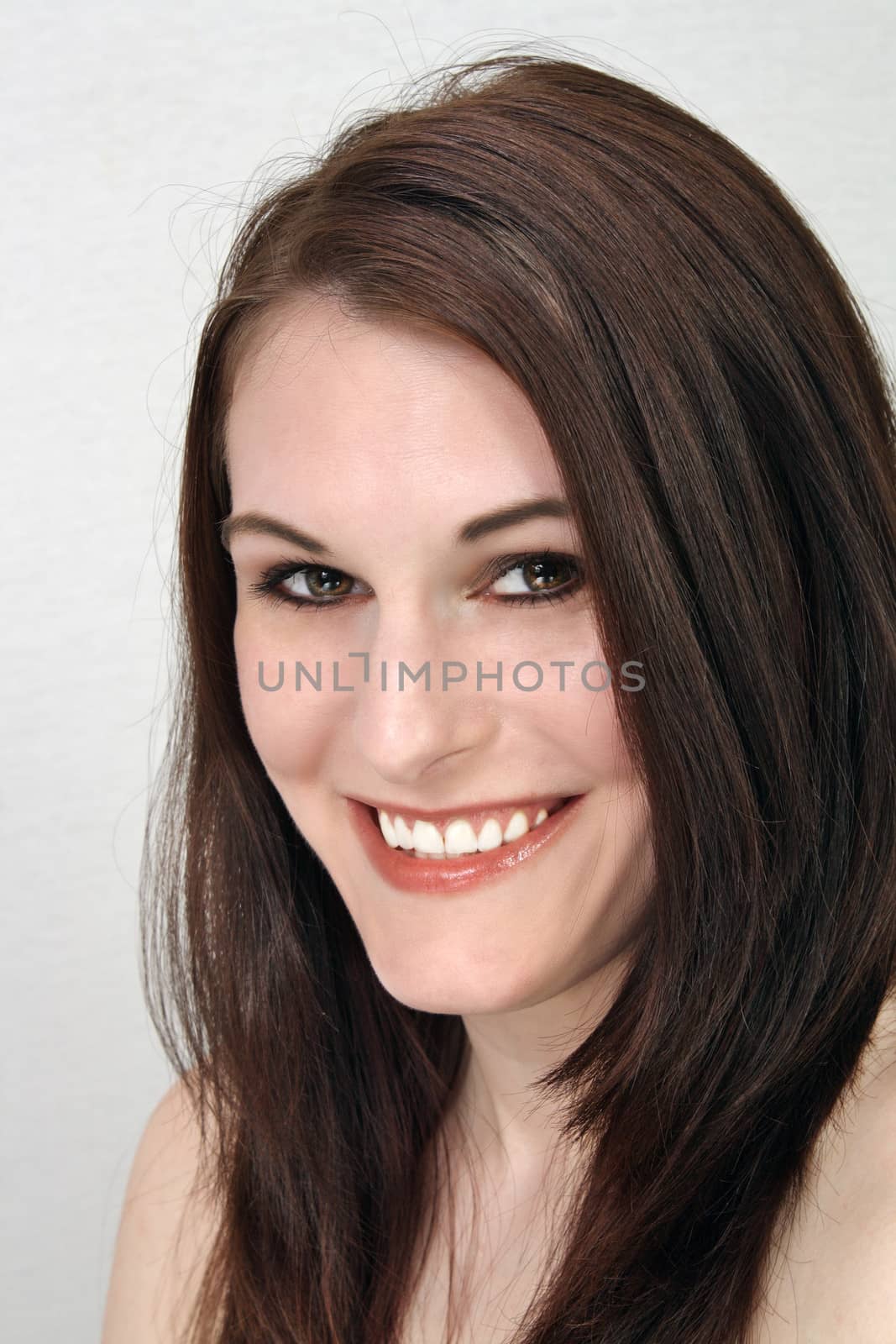 A close-up of a lovely young brunette with a bright, warm smile.