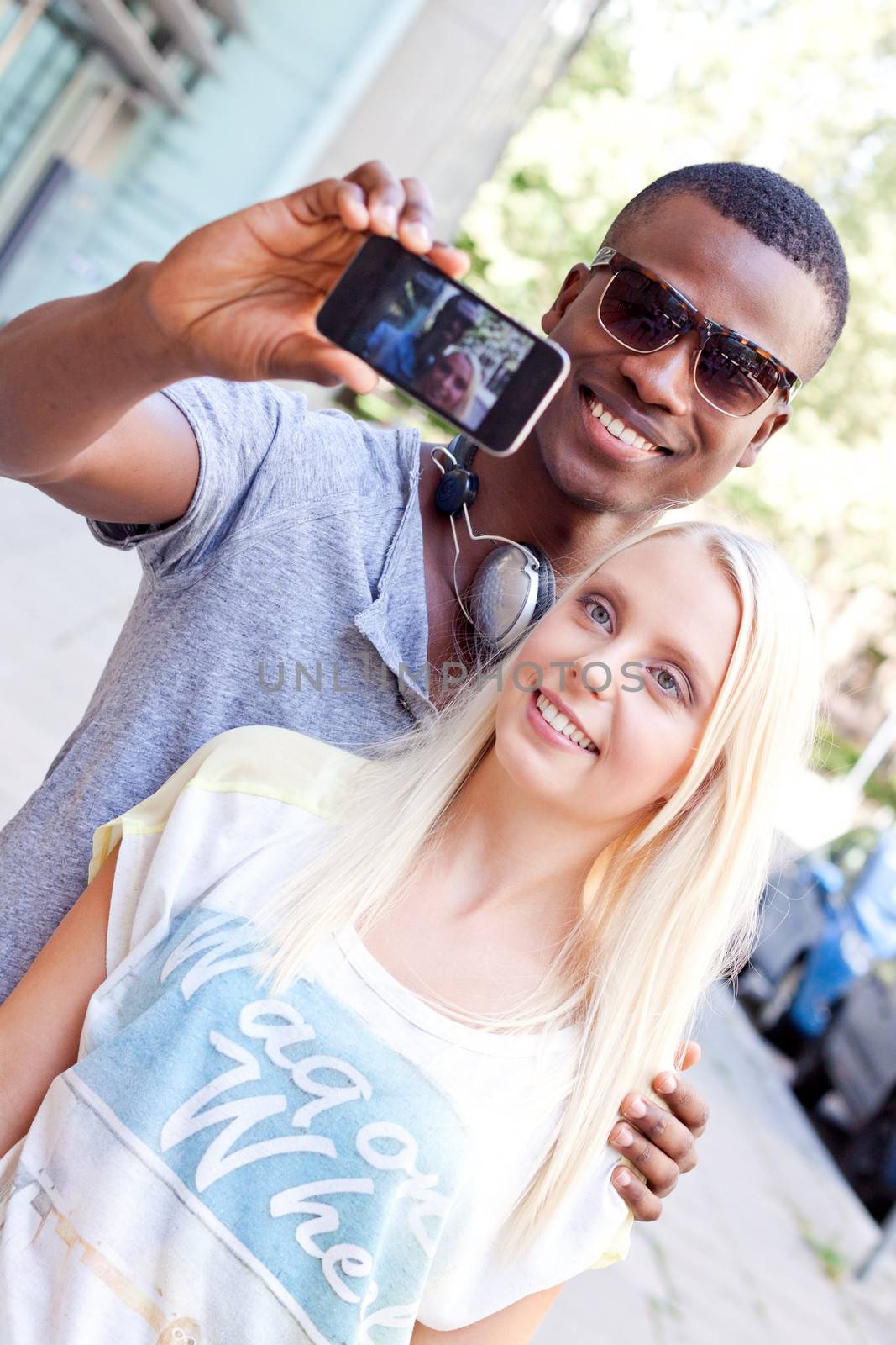 young smiling multiracial couple taking foto by smartphone outdoor in summer