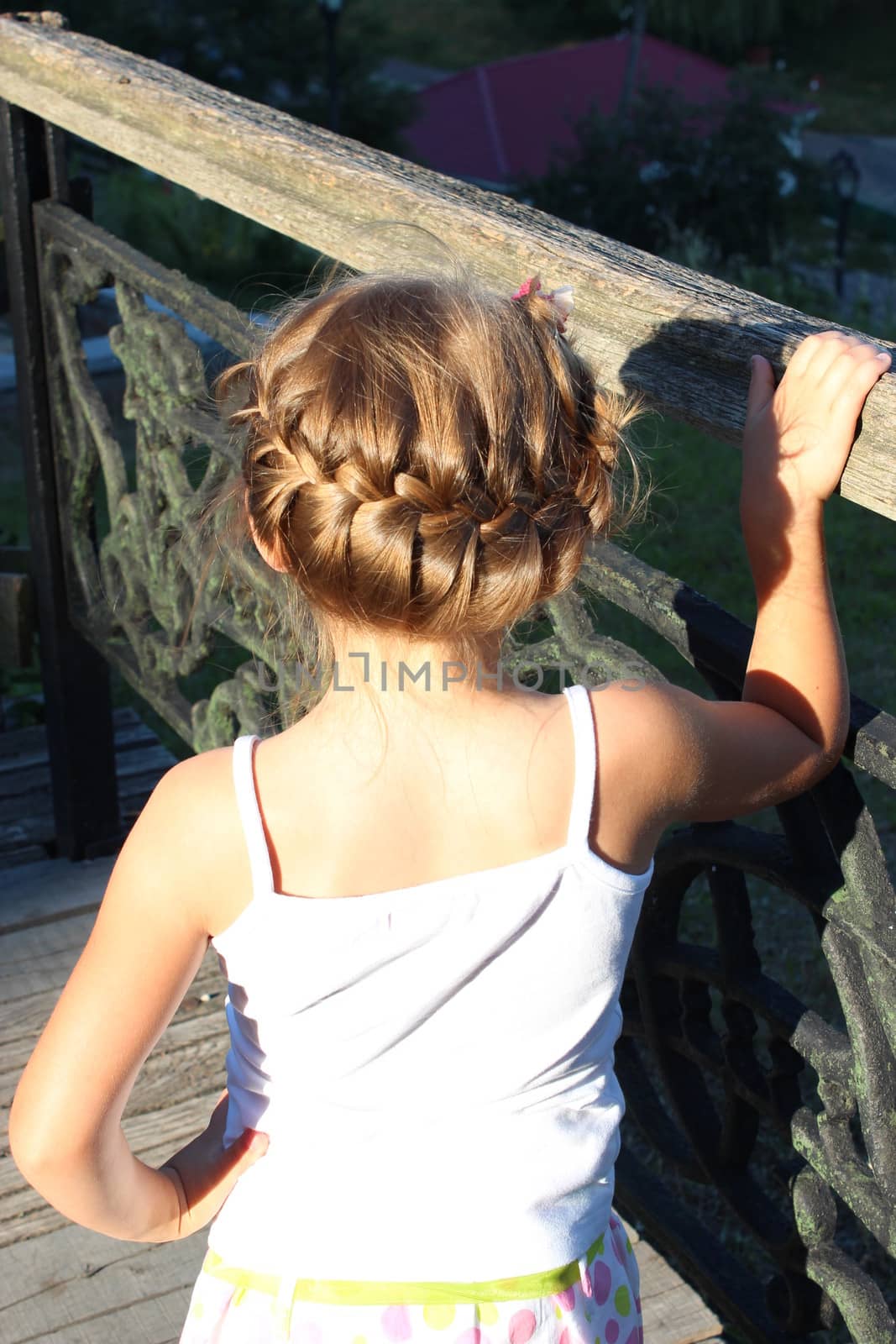 the little girl with nice hair-do standing beside railing