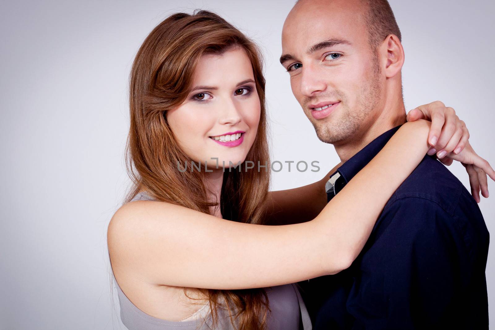 young attractive couple in love embracing portrait on grey backgound 