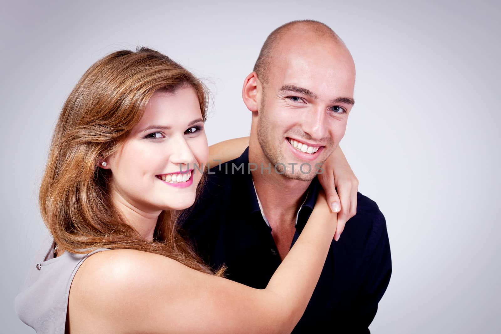 young attractive couple in love embracing portrait on grey backgound 