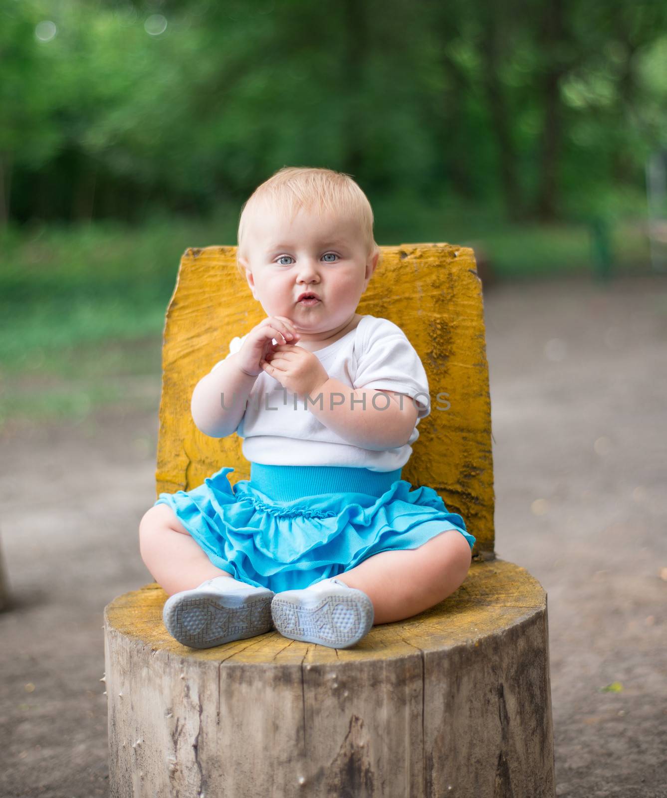 cute beautifil baby sitting on a tree stump