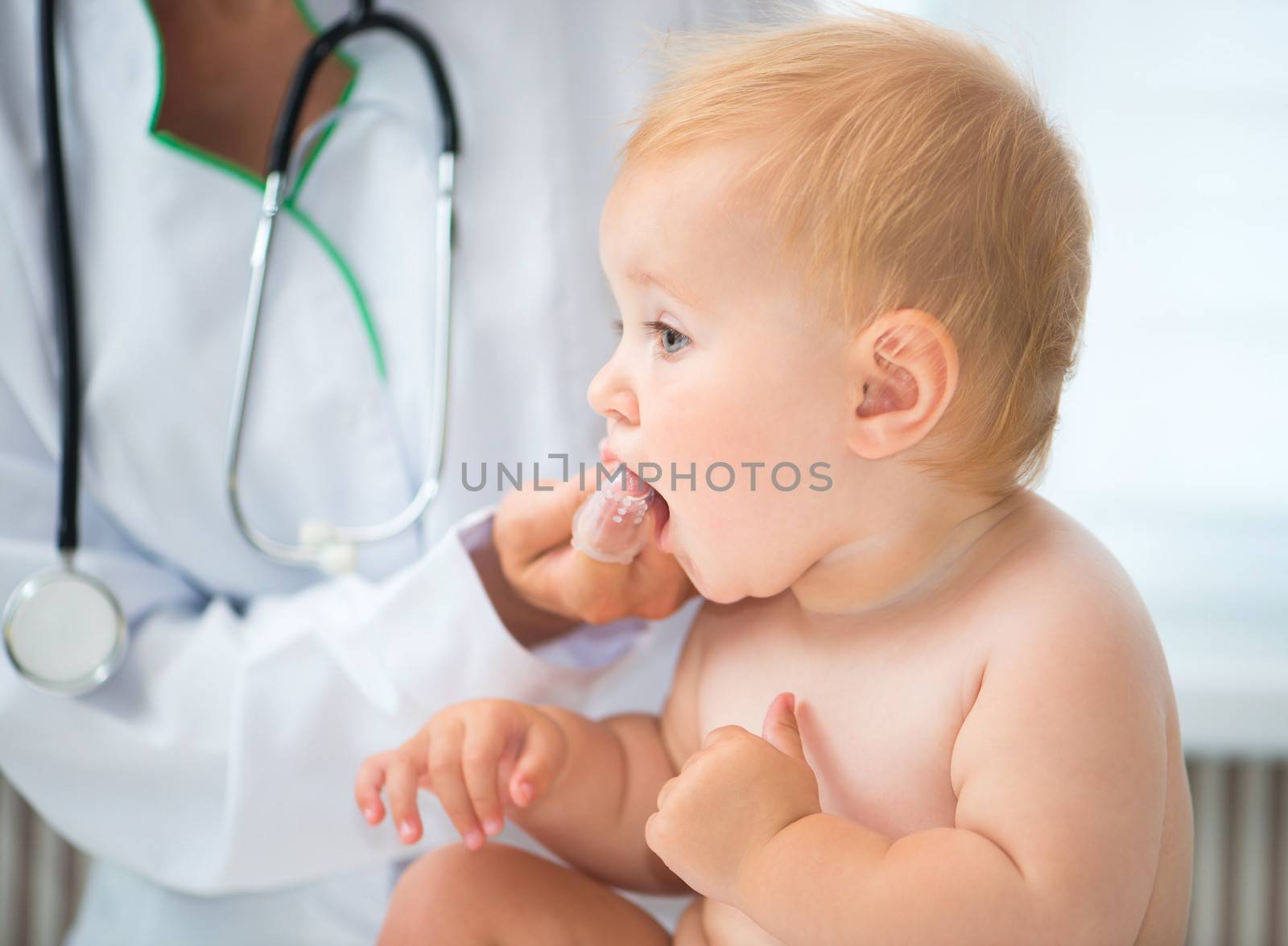 doctor cleans baby teeth with a special brush