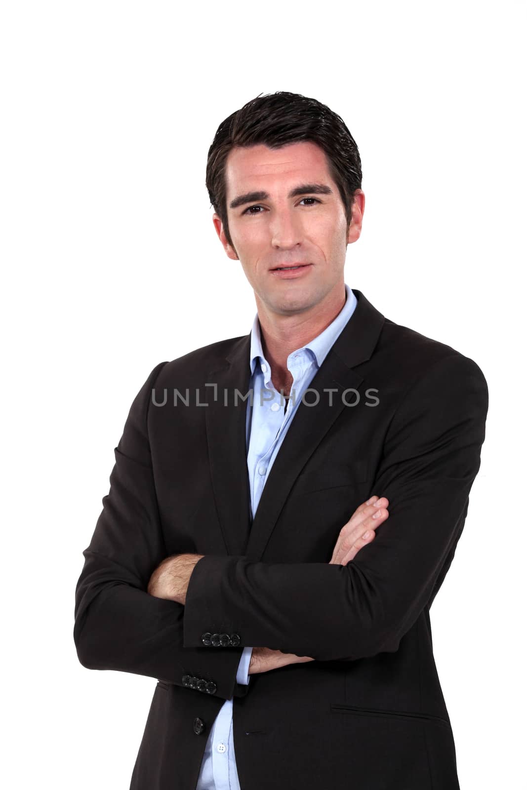 elegant man standing cross-armed against white background by phovoir