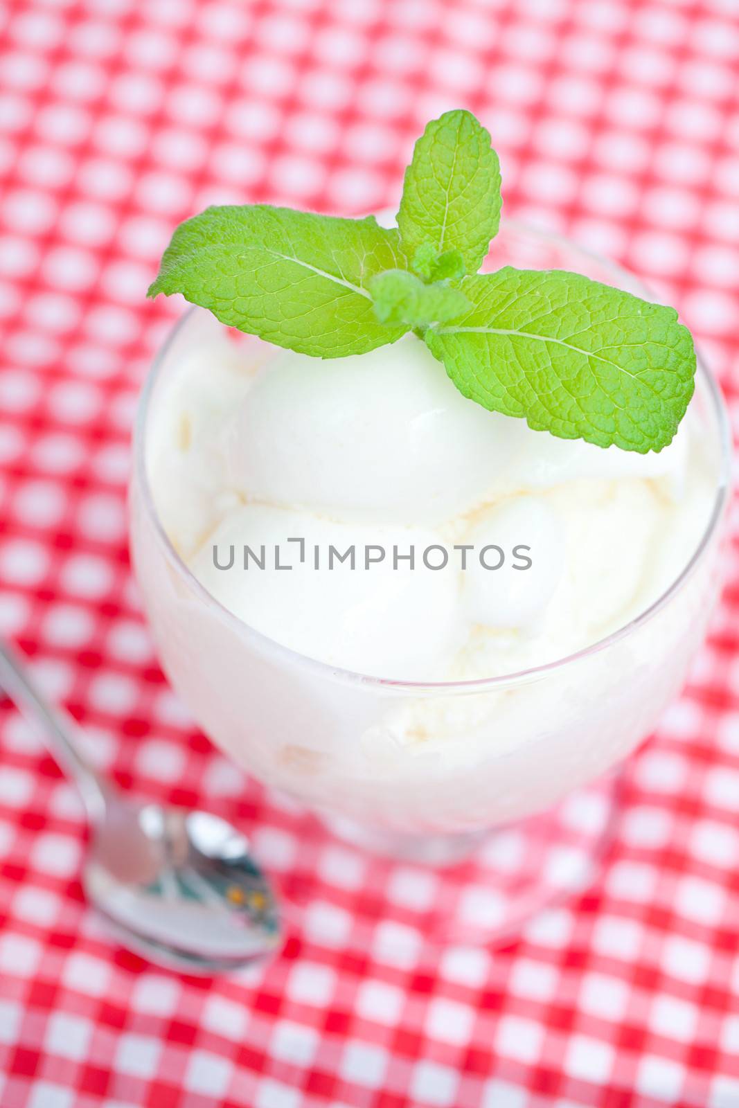 ice cream with mint in a glass bowl  and spoon on plaid fabric