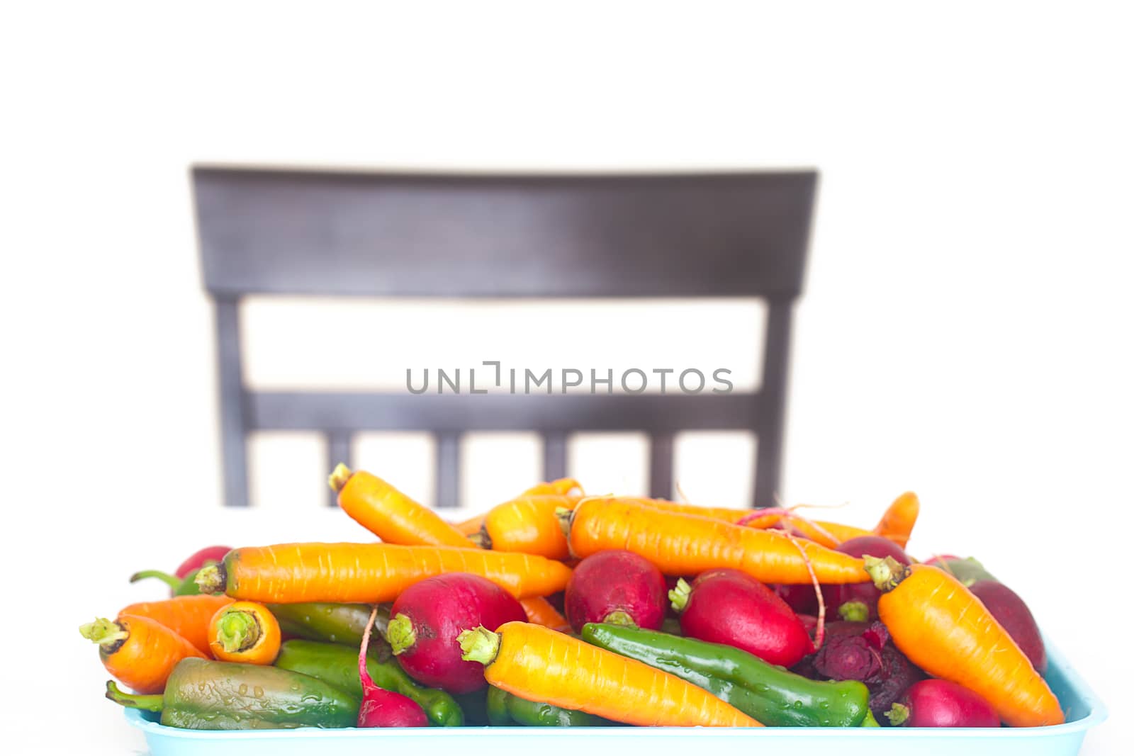heap of vegetables on a table and a chair isolated on white