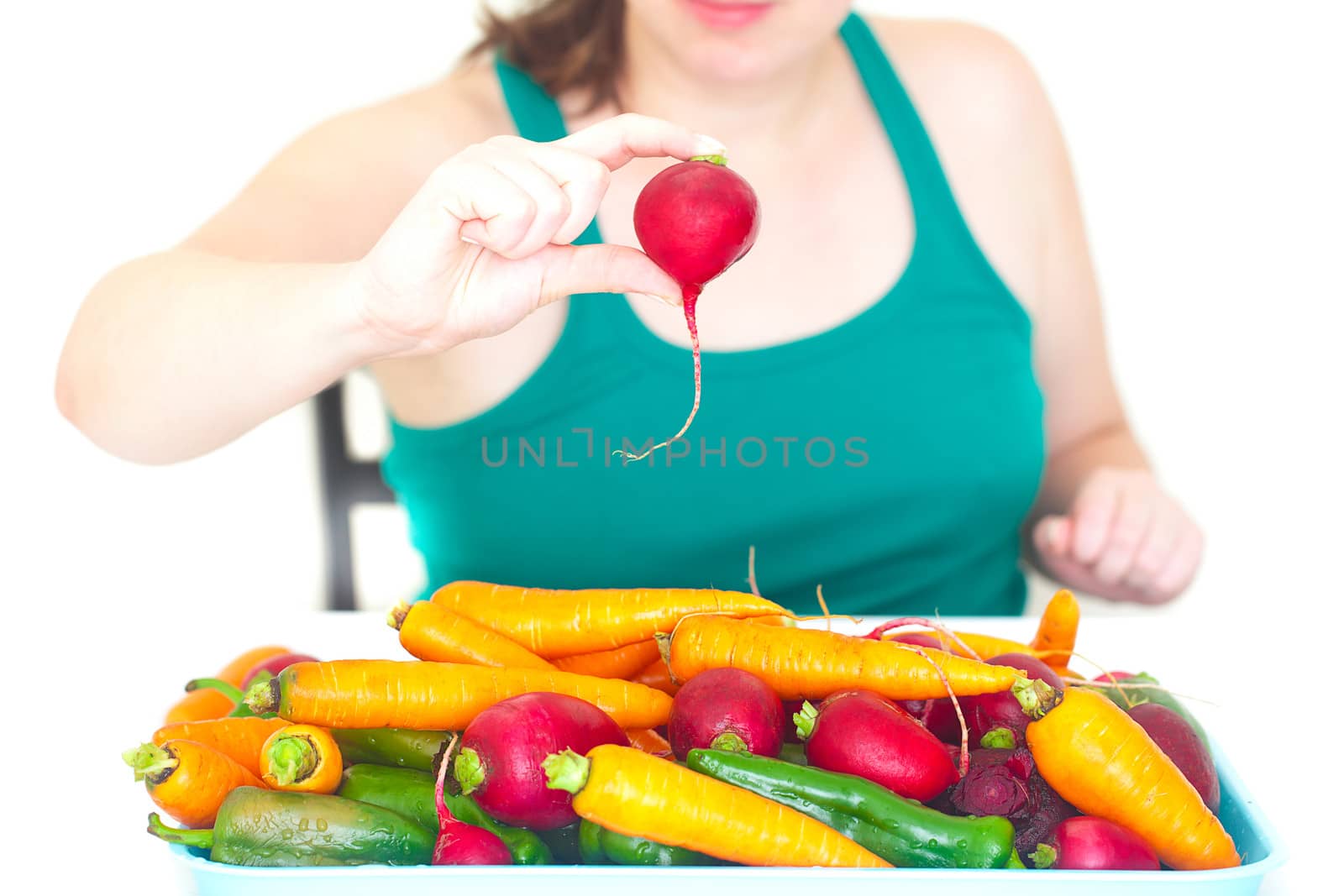 young woman holding in the hand radish and the heap of vegetables