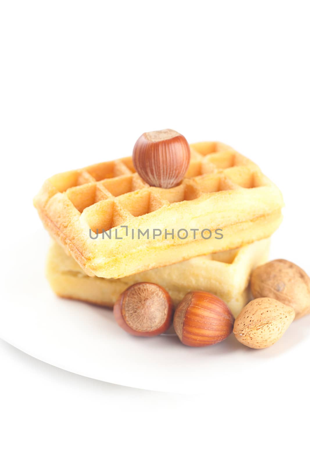 Belgian waffles and nuts on a plate isolated on white