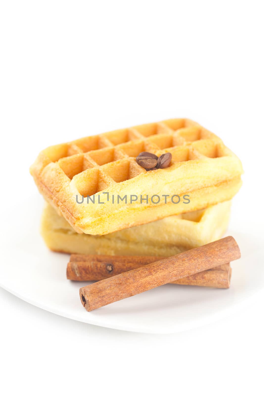 Belgian waffles,coffee beans and cinnamon on a plate isolated on white