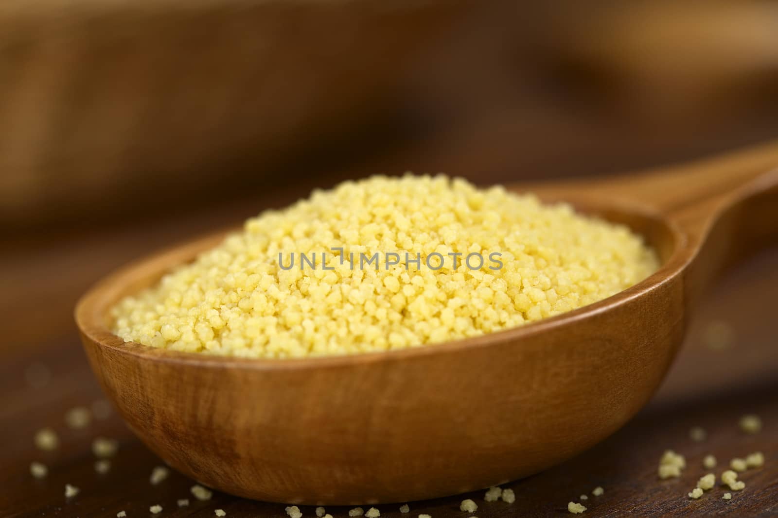 Raw couscous on wooden spoon (Very Shallow Depth of Field, Focus one third into the couscous)