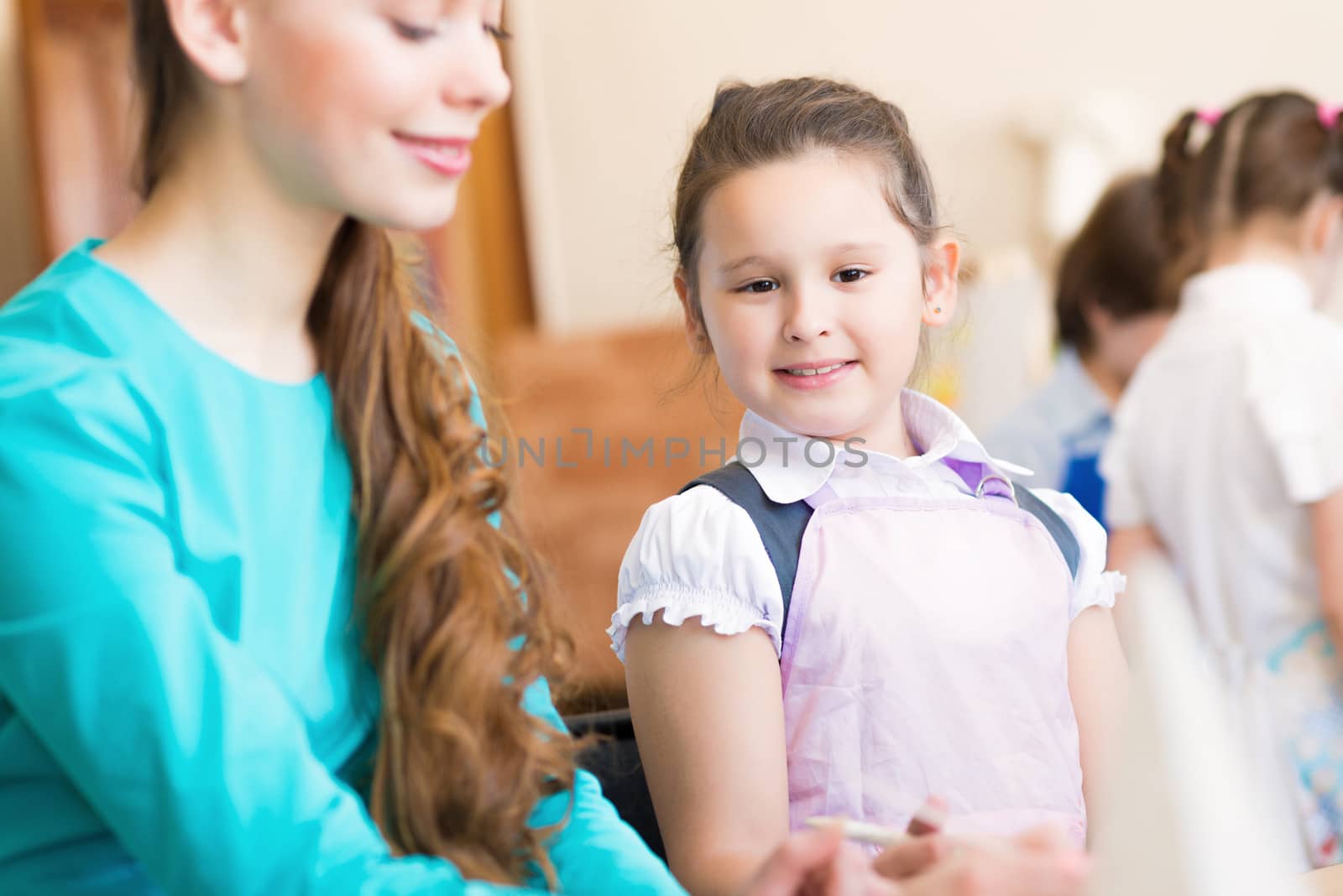 girl in the school, near the teacher and other children