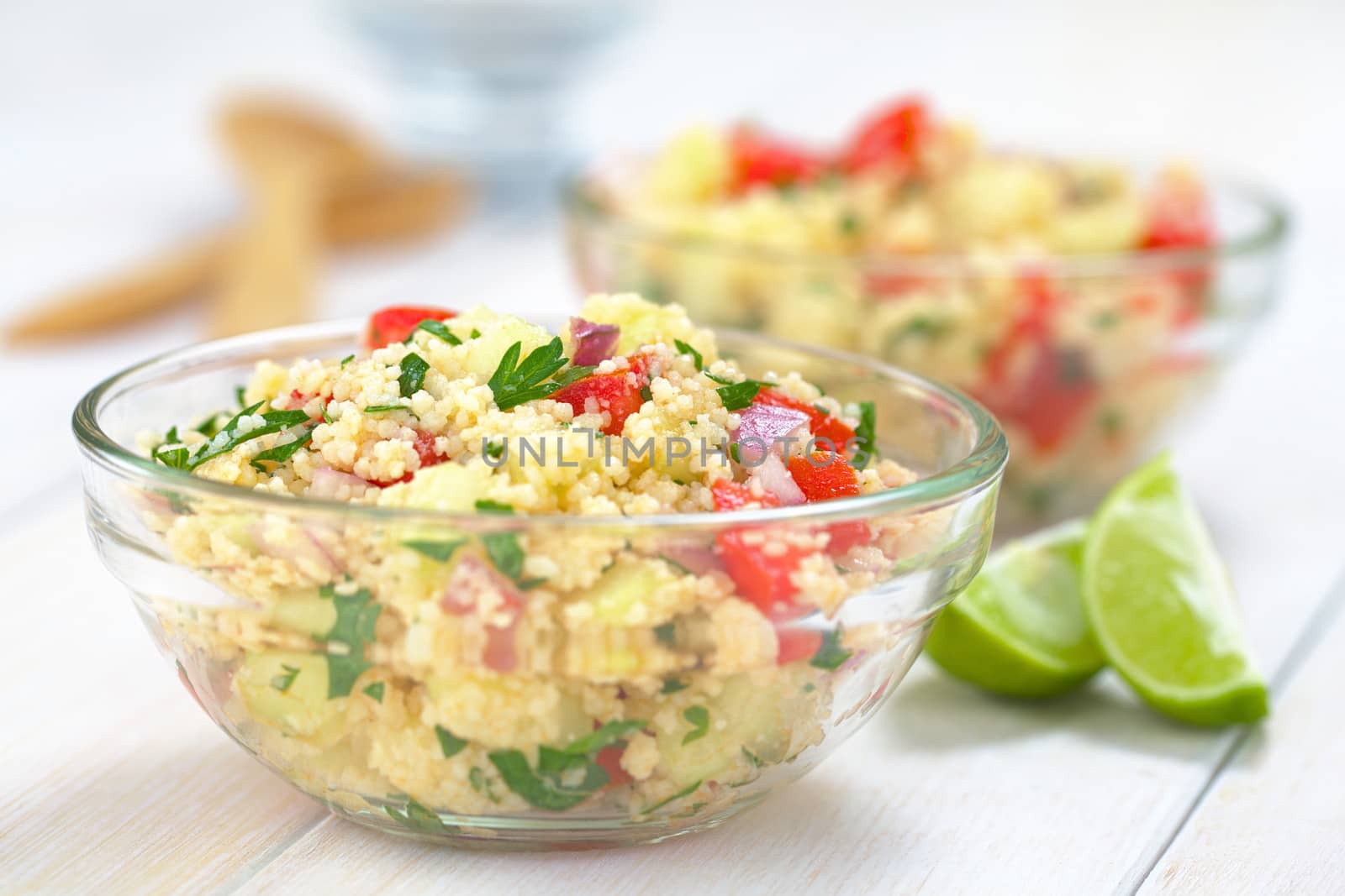 Fresh homemade Tabbouleh, an Arabian vegetarian salad made of couscous, tomato, cucumber, onion, garlic, parsley and lemon juice served in a glass bowl (Selective Focus, Focus one third into the tabbouleh)