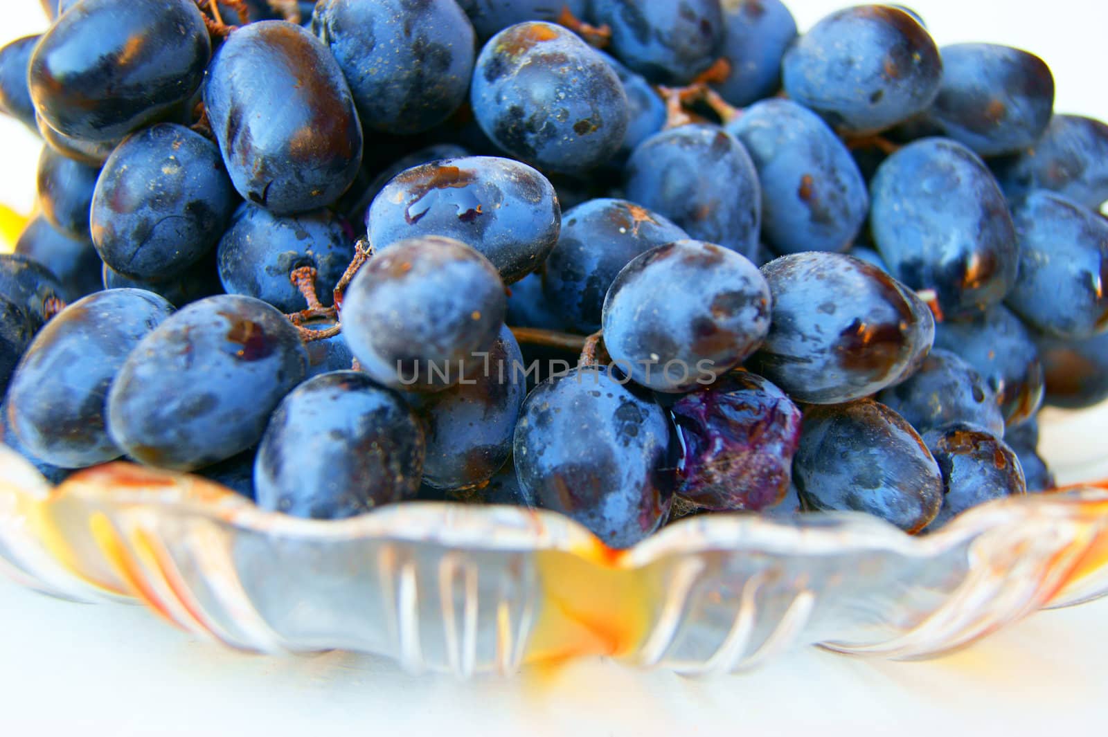 Ripe grape on plate on white background