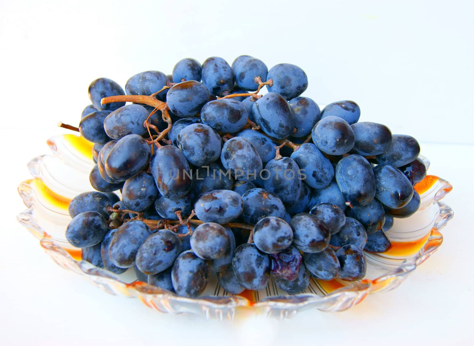 Ripe grape on plate on white background