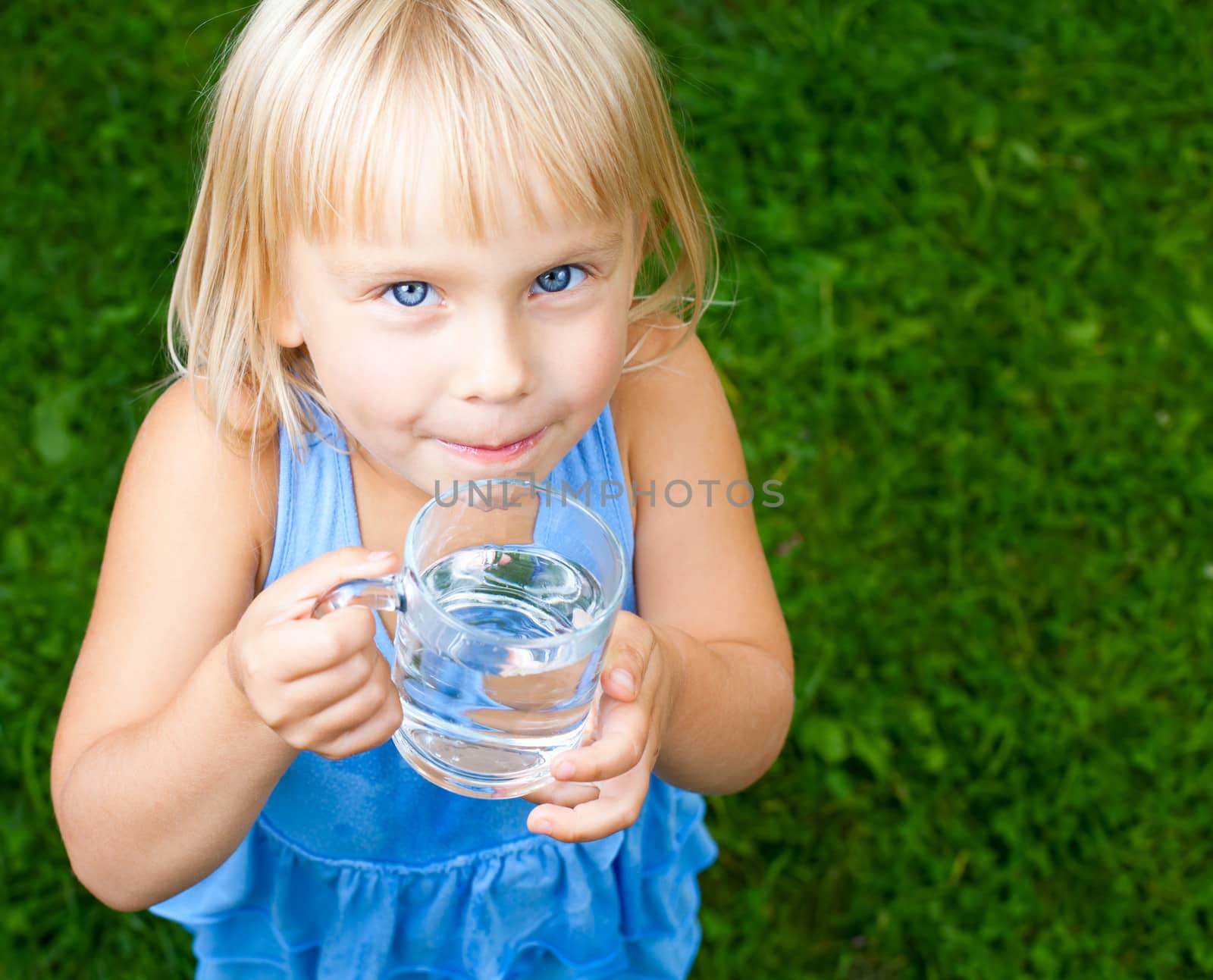 Little girl holding glass of water outdoors