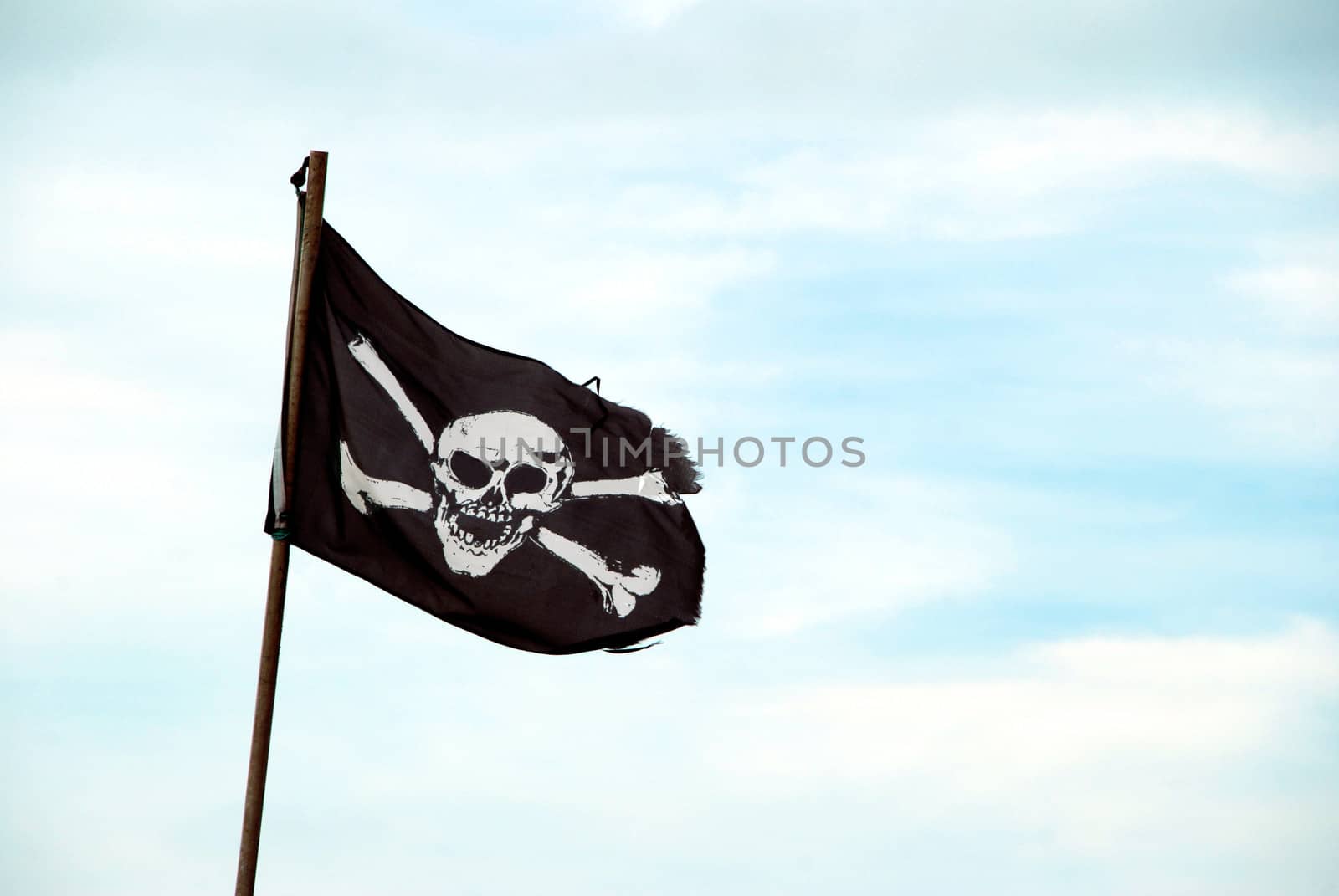 Ragged pirate flag with skull and crossbones flying from flagpole