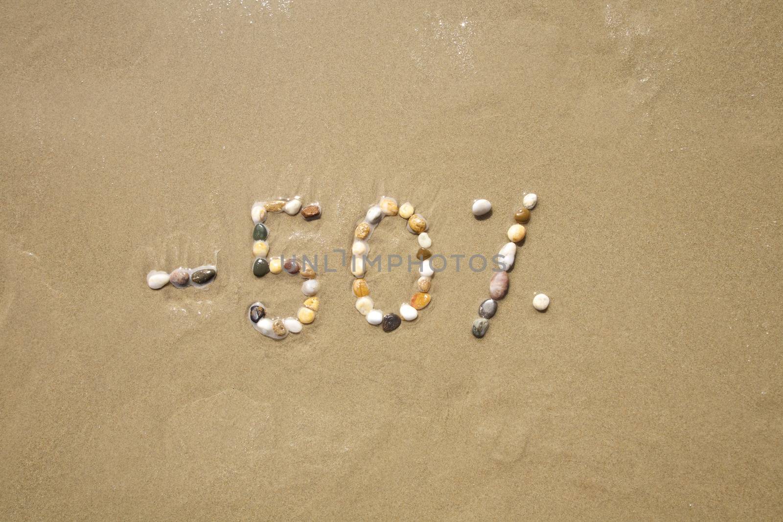 fifty percent discount word writing with small stones on sand beach ground