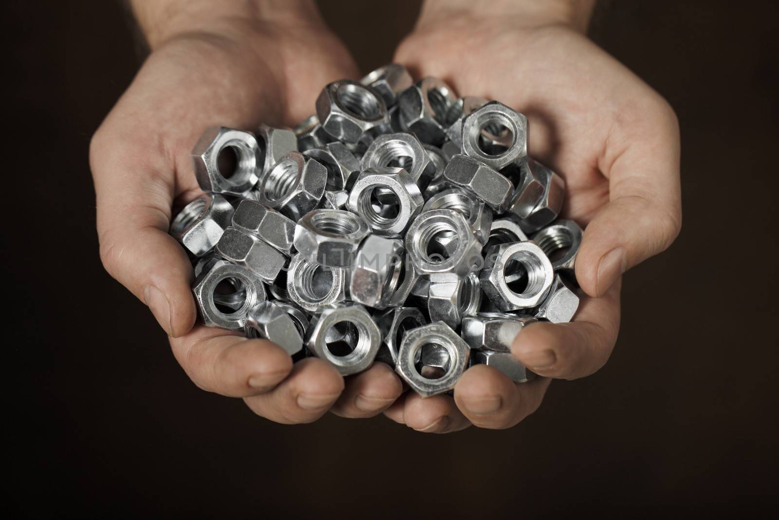 Man holding metallic nuts in his hands.