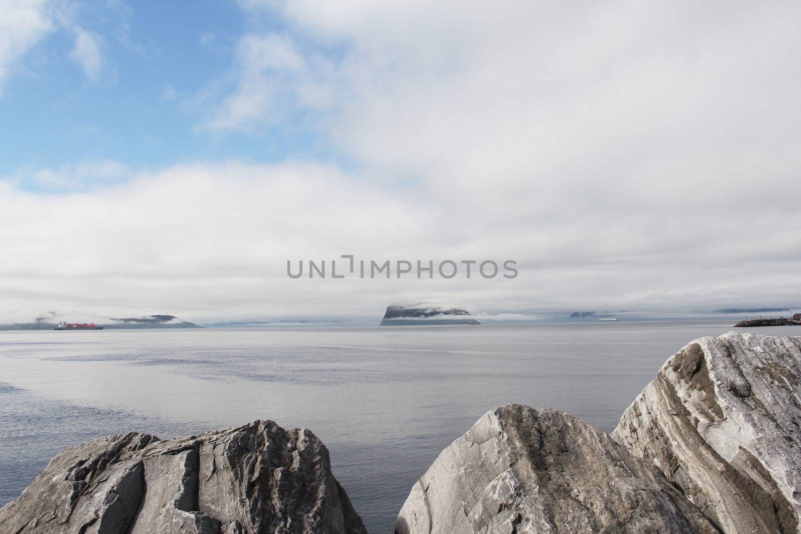 Morning fjord landscape with mountains and fog over water