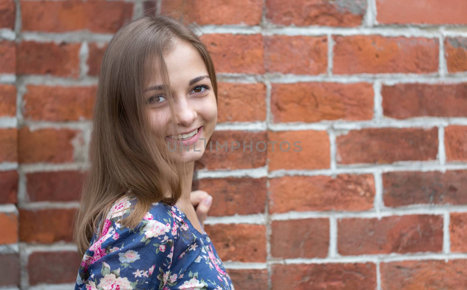 portrait of a beautiful young girl on a background of red bricks.