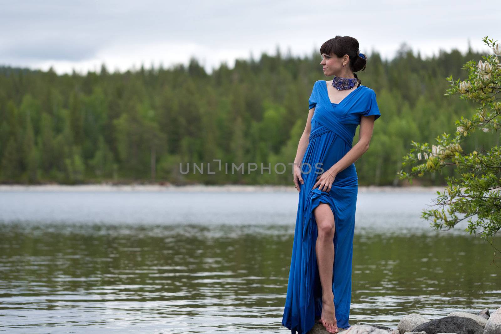 girl in a luxurious evening dress on the lake shows a slim leg