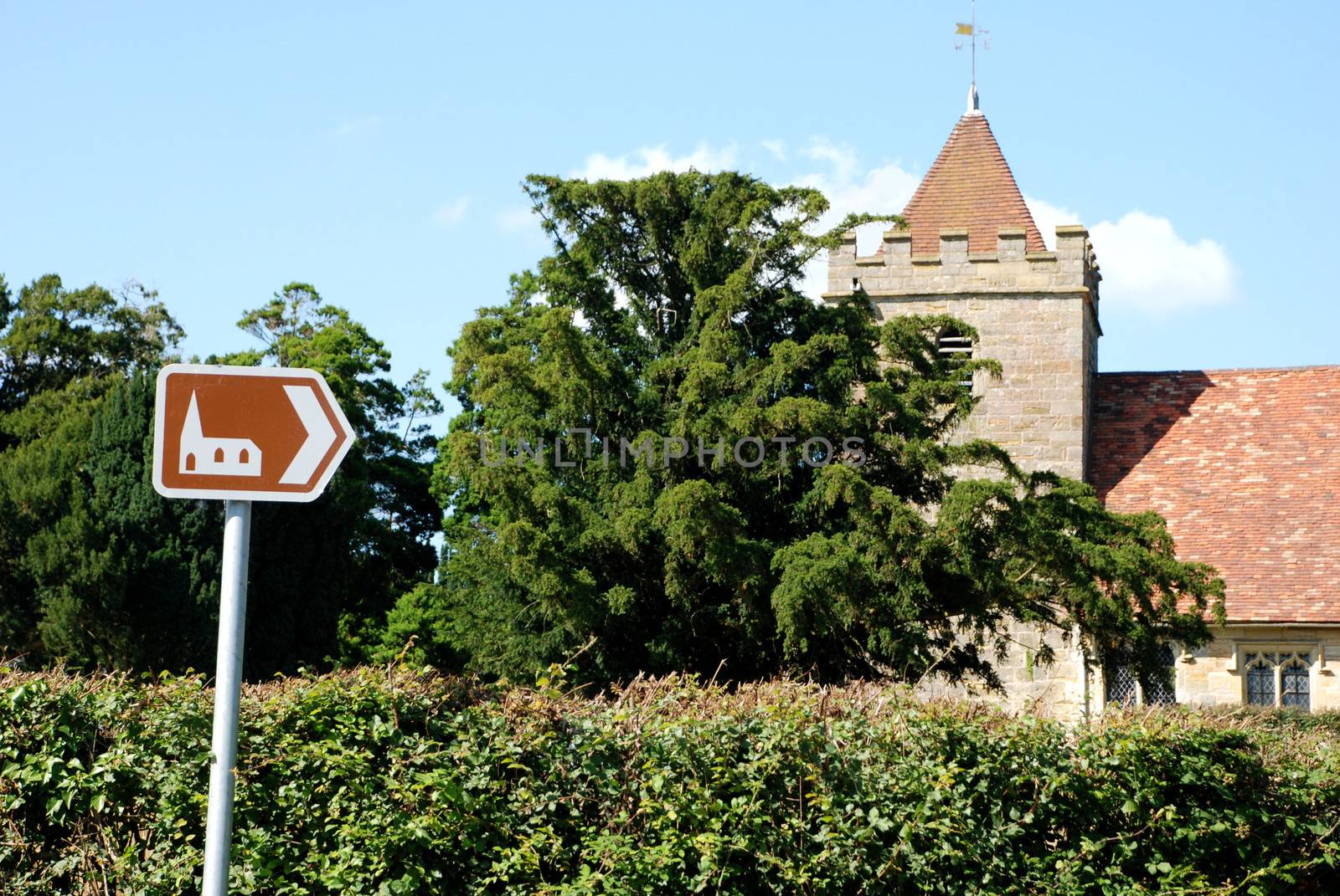 Brown tourist sign pointing towards the historic church of St Thomas a Becket in Kent