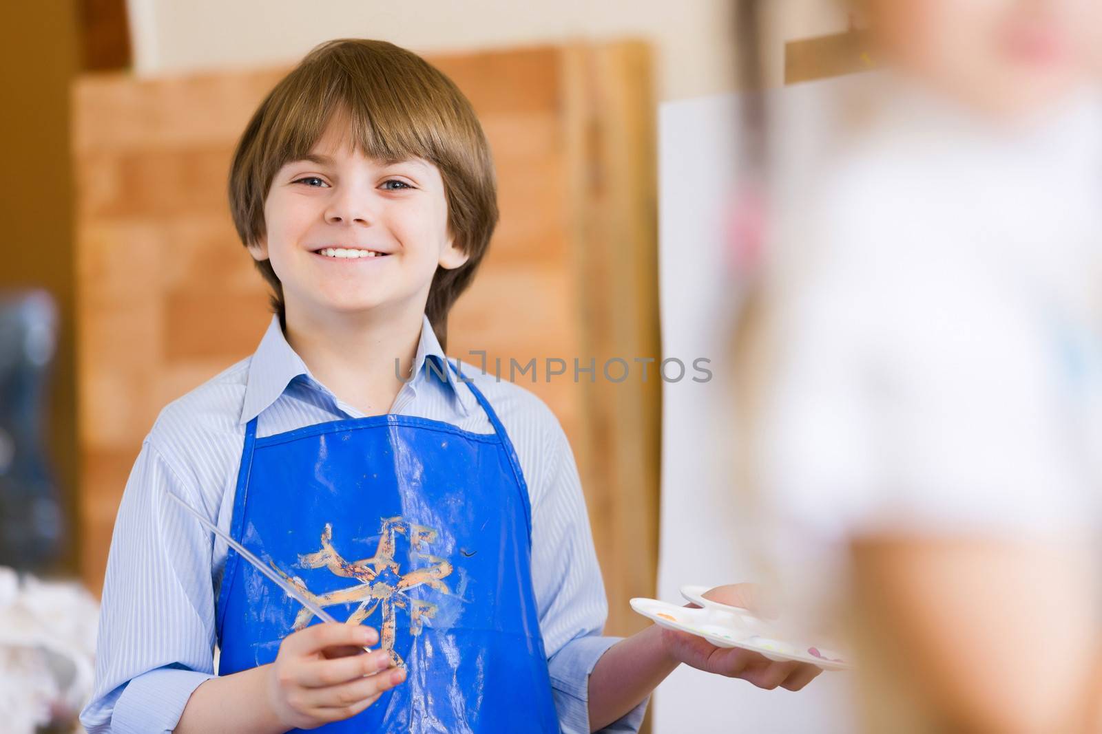 Image of little cute boy painting pictures at kindergarten