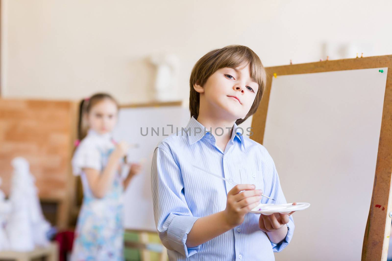 Image of little cute boy painting pictures at kindergarten