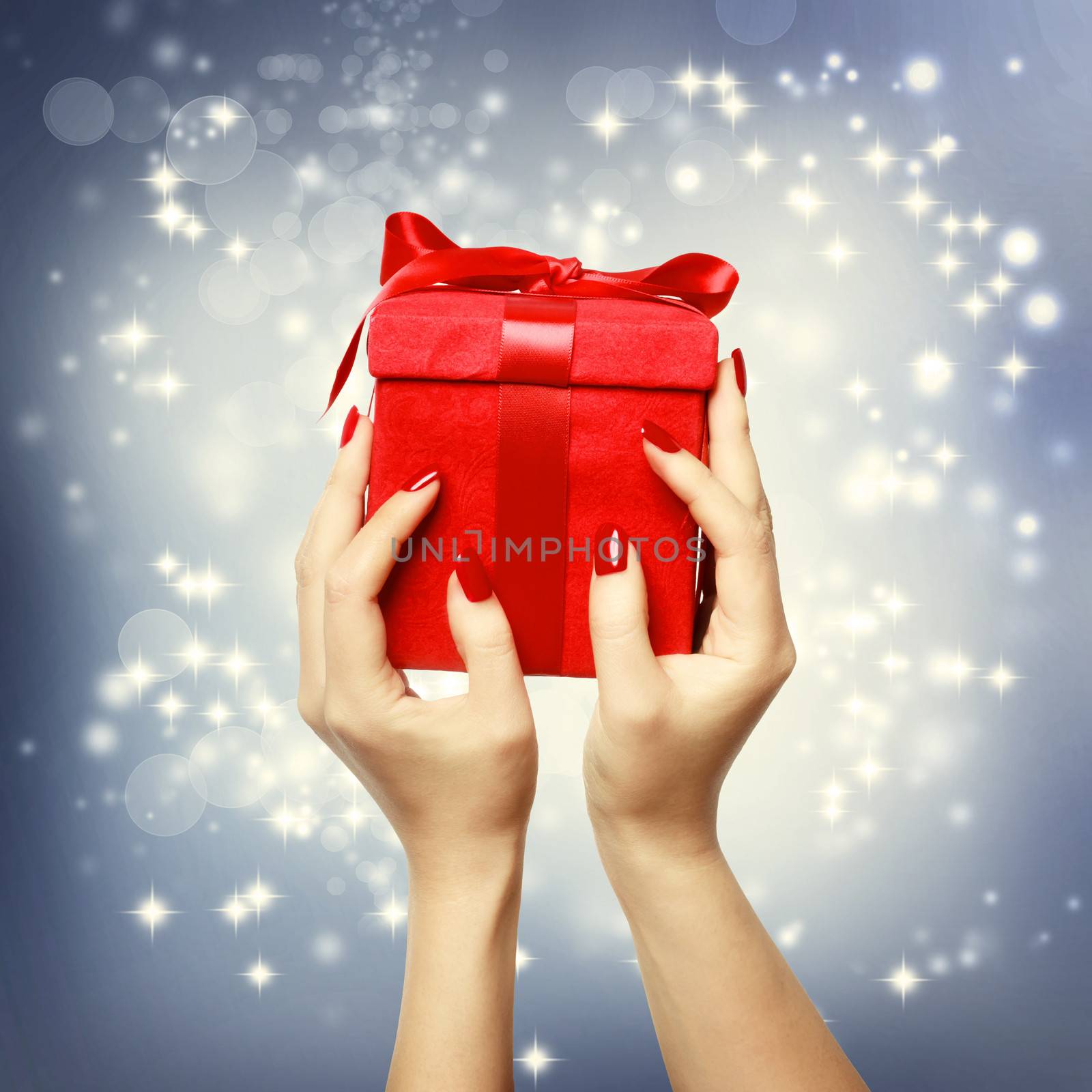 Woman's hands holding up red present box on Christmas on shinning background