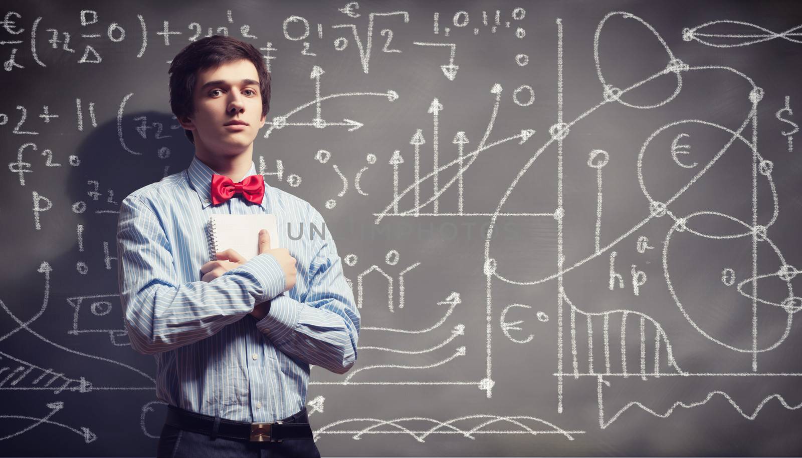 Image of thoughtful male student holding notebook in classroom