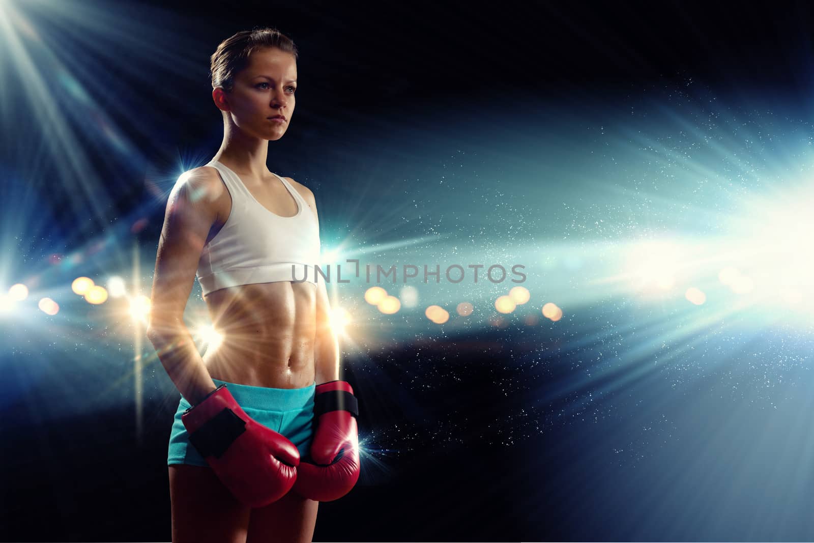 Young pretty boxer woman standing in light flashes