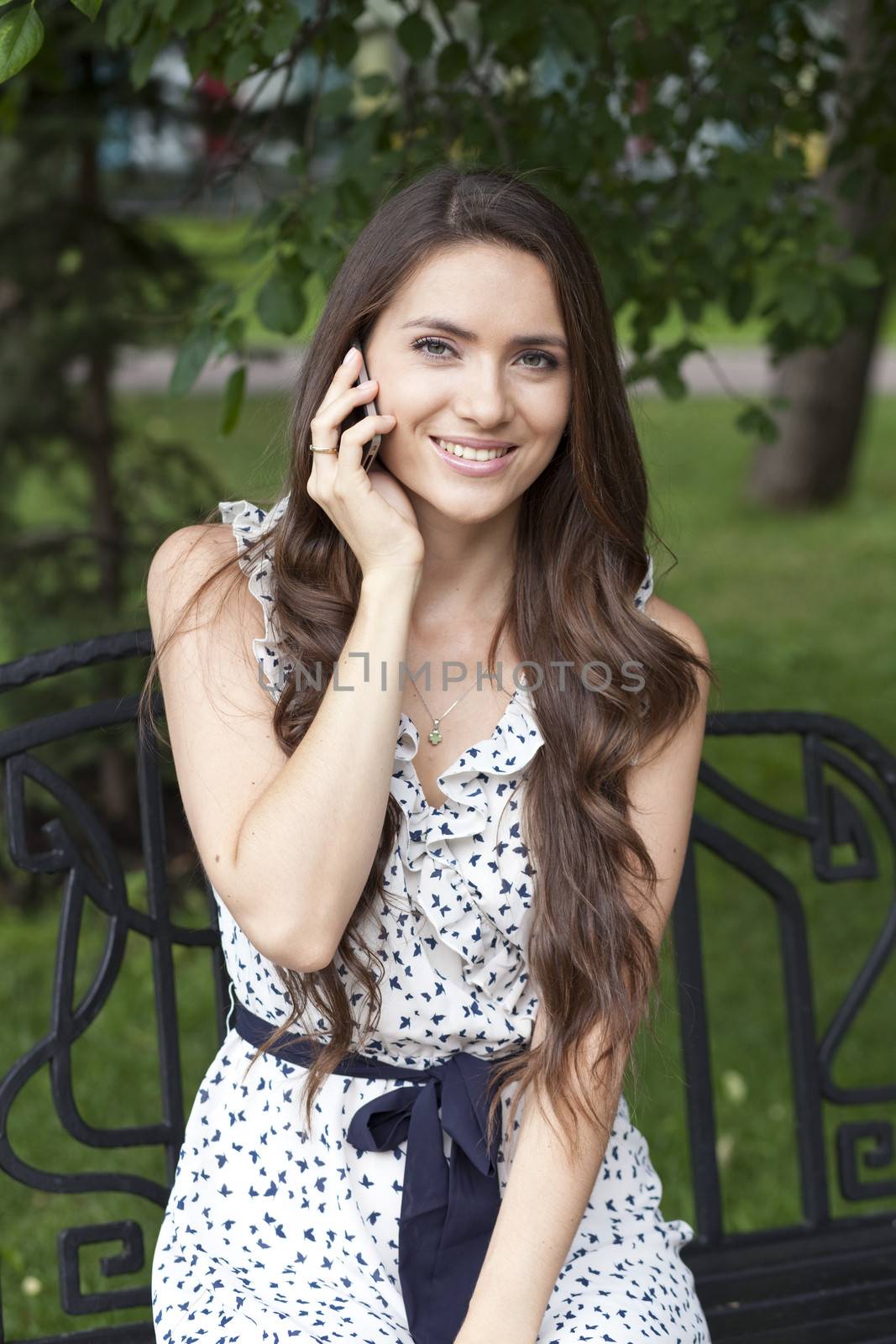 Brunette sitting on a bench in a summer park