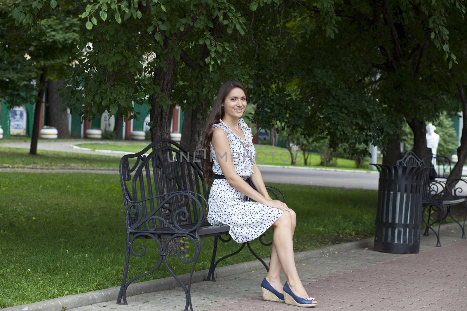 Beautiful young woman sits on a bench