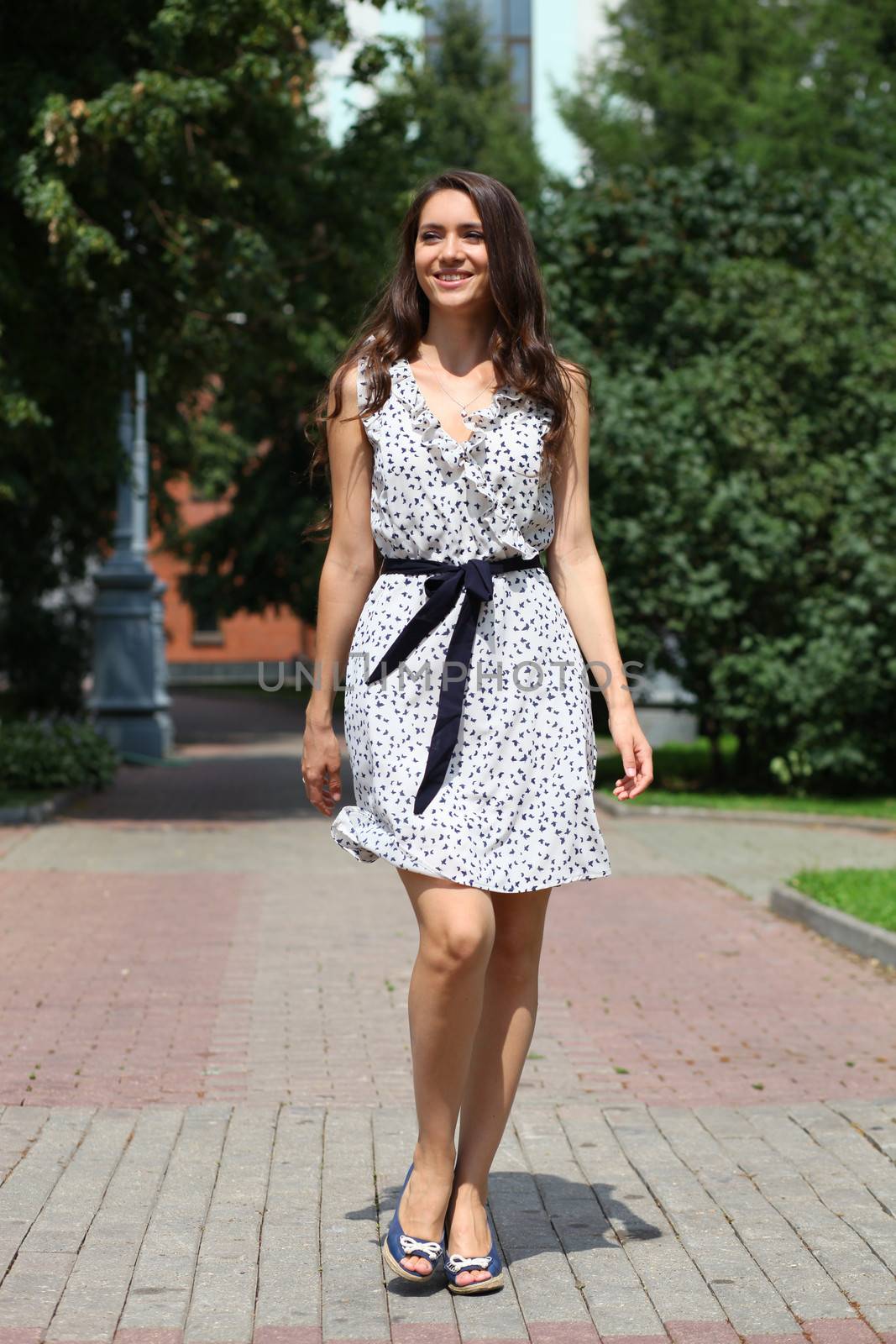 Beautiful young woman walking on the summer park by andersonrise