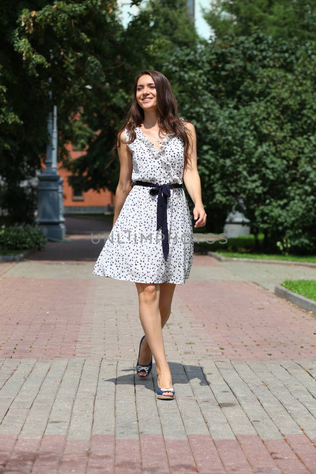 Beautiful young woman walking on the summer park by andersonrise