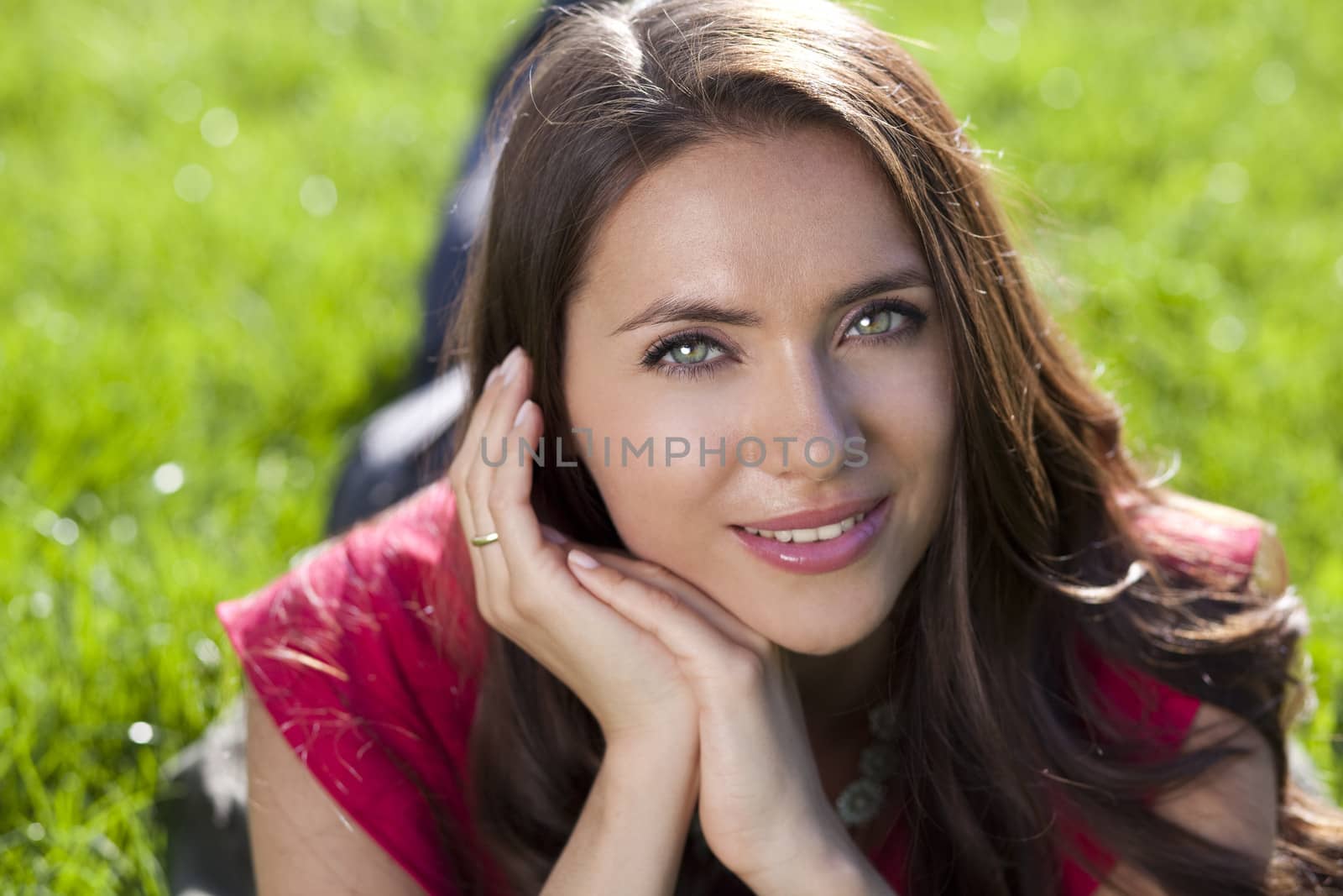 Portrait of young woman lying on a green lawn