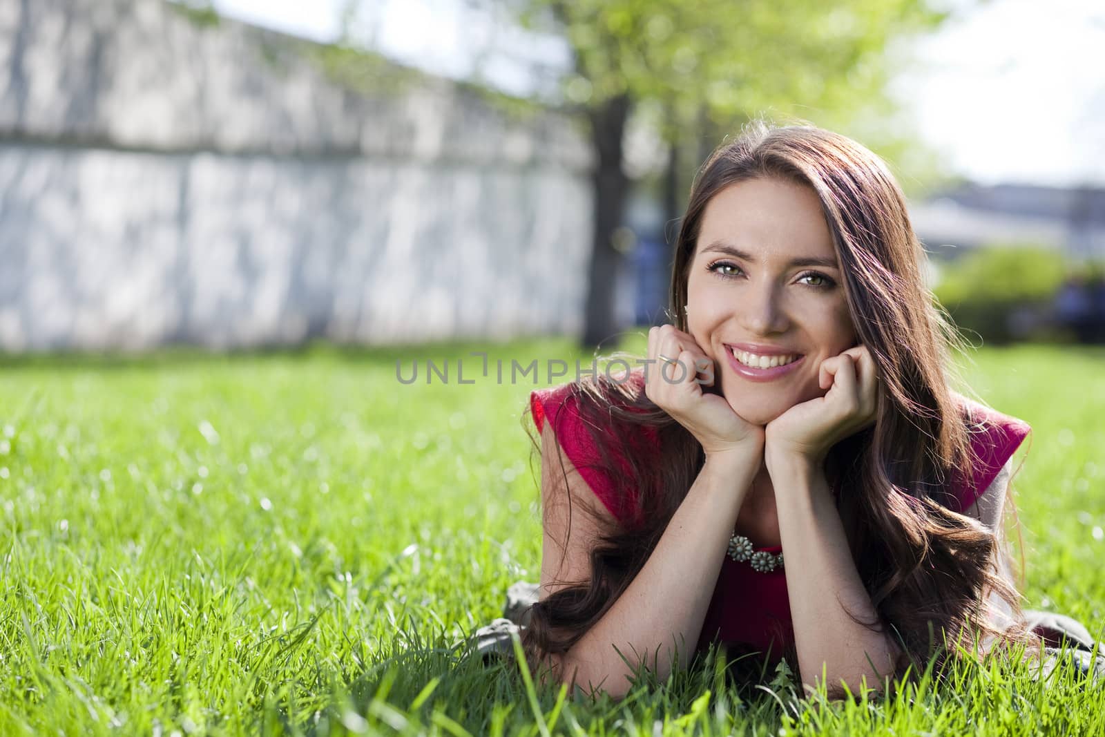Portrait of young woman lying on a green lawn by andersonrise