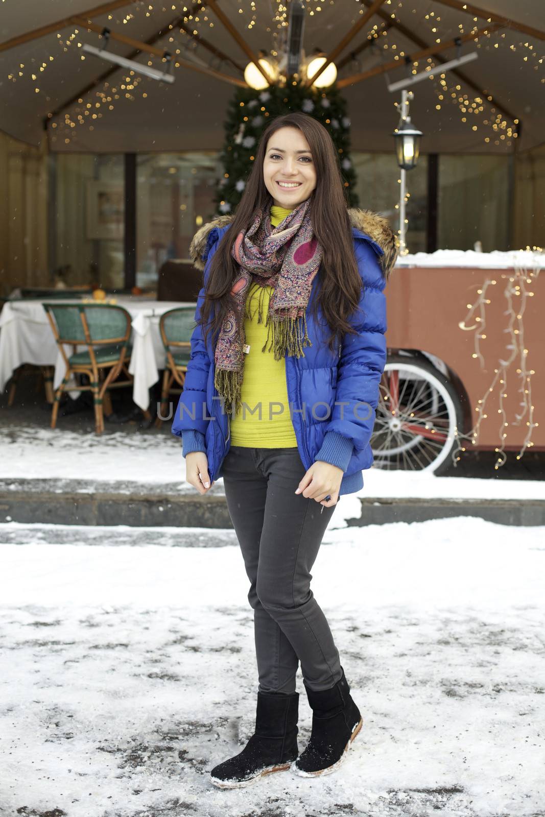 Caucasian young adult female smiling and walking down snow covered street