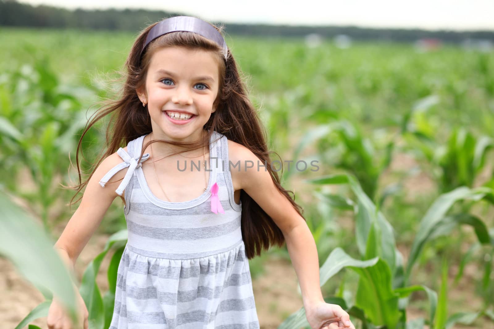 Joyful little girl running through the corn field