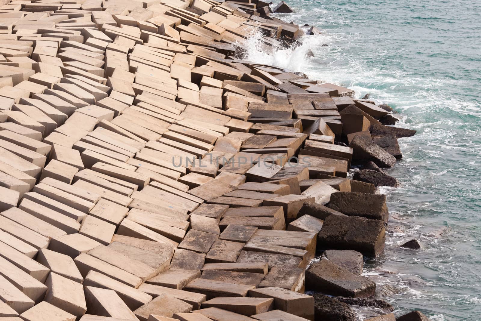 Concrete blocks laid haphazardly forming a protective coastal seawall to prevent erosion from tides and waves as an architectural abstract