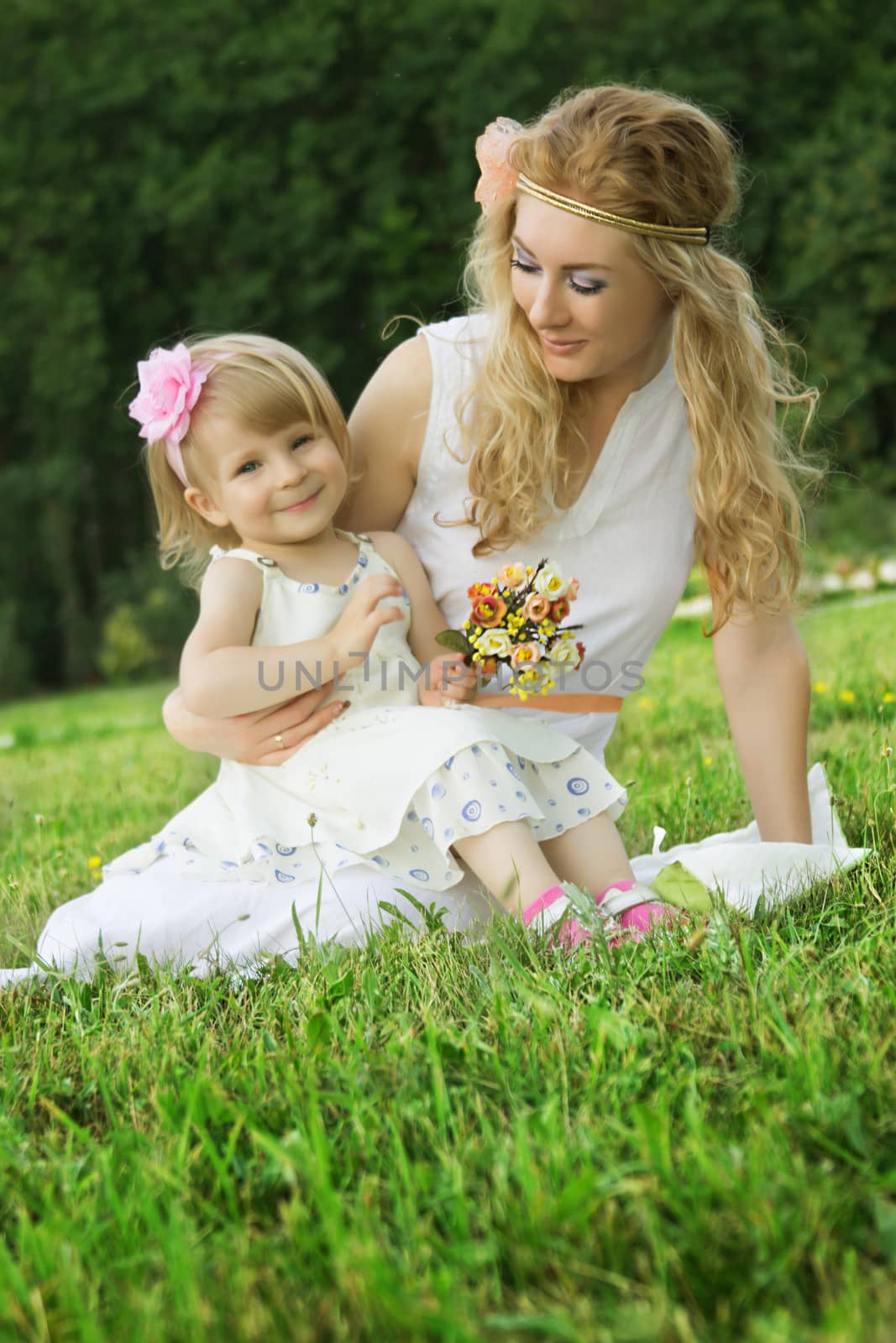 Romantic mother and smiling daughter sitting on grass