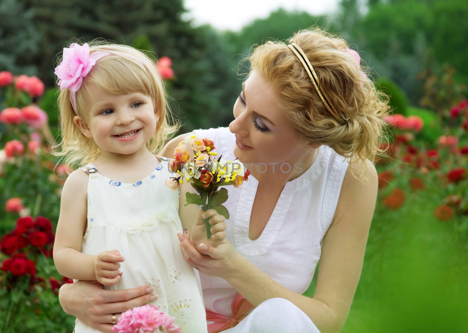 Mother and baby girl among pink rose garden