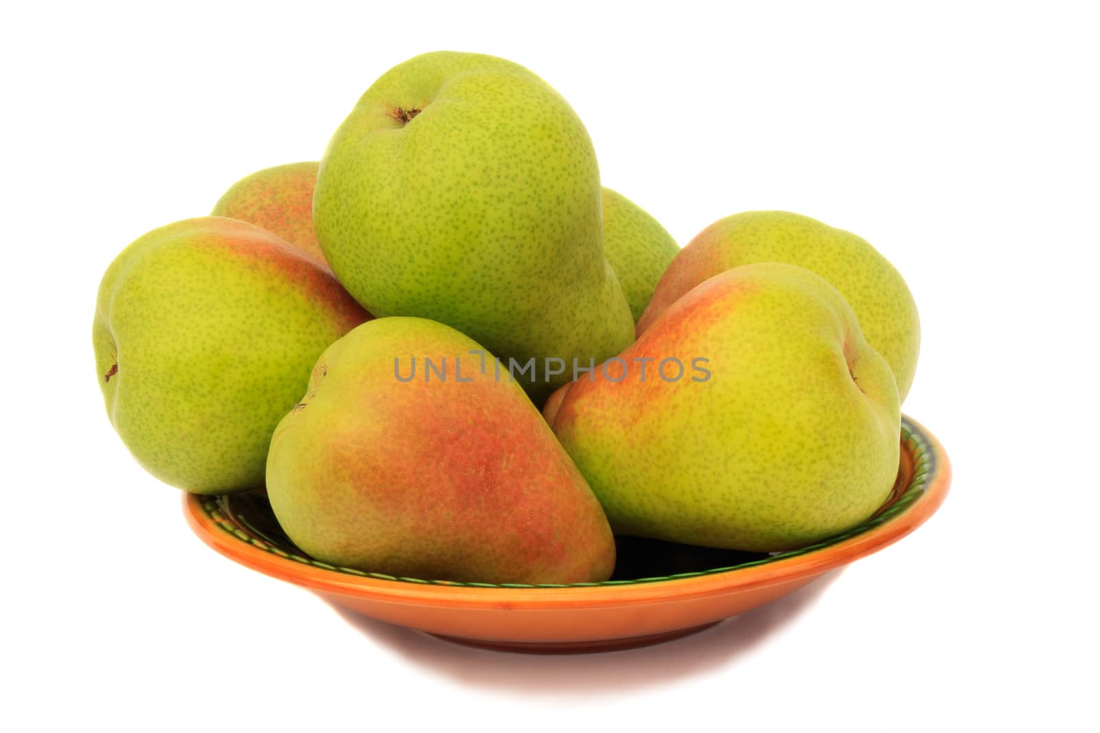 Large ripe yellow pears on a ceramic plate. Presented on a white background.