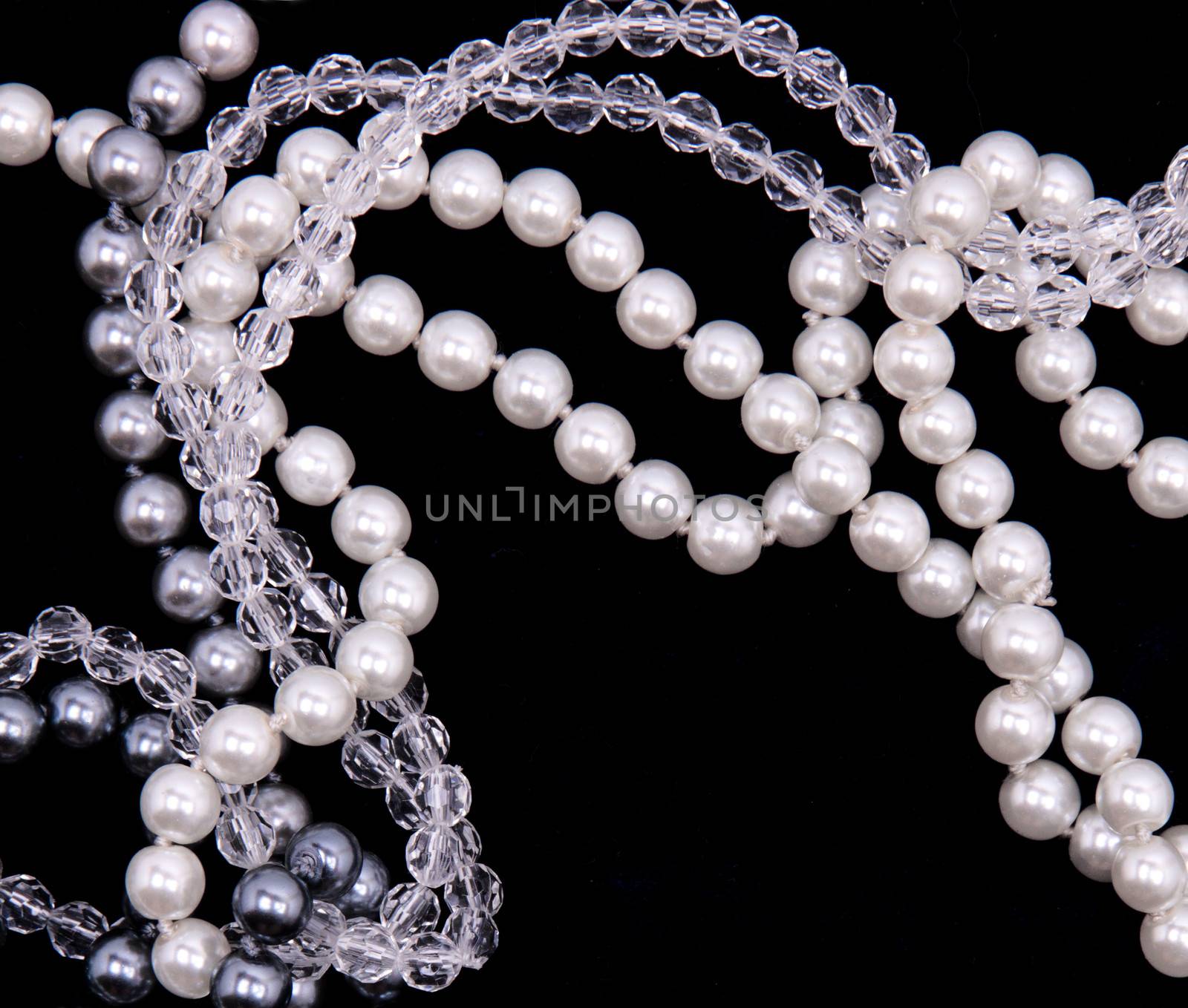 White, black and grey pearls on the black silk background 