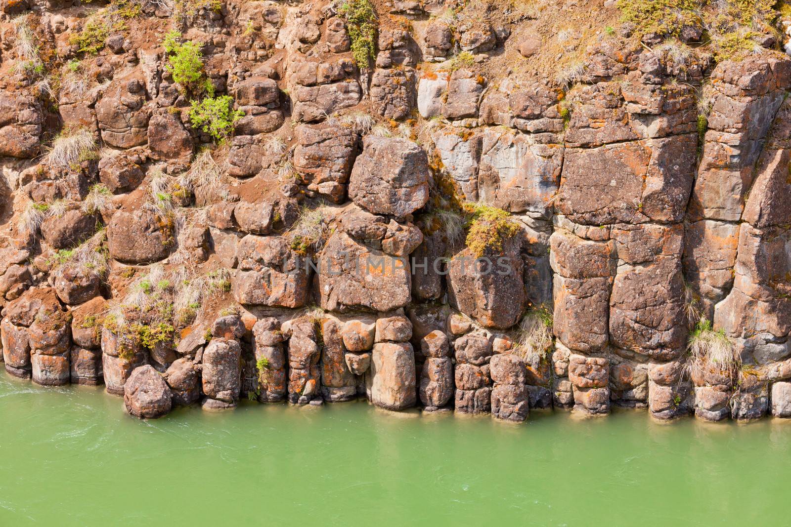 Close-up of weathered geologic basalt rock cliff wall of Miles Canyon with water of Yukon River Yukon Territory Canada