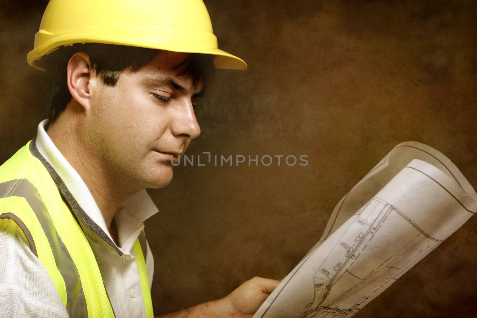 Male builder site foreman reading architectural industrial plans by lovleah
