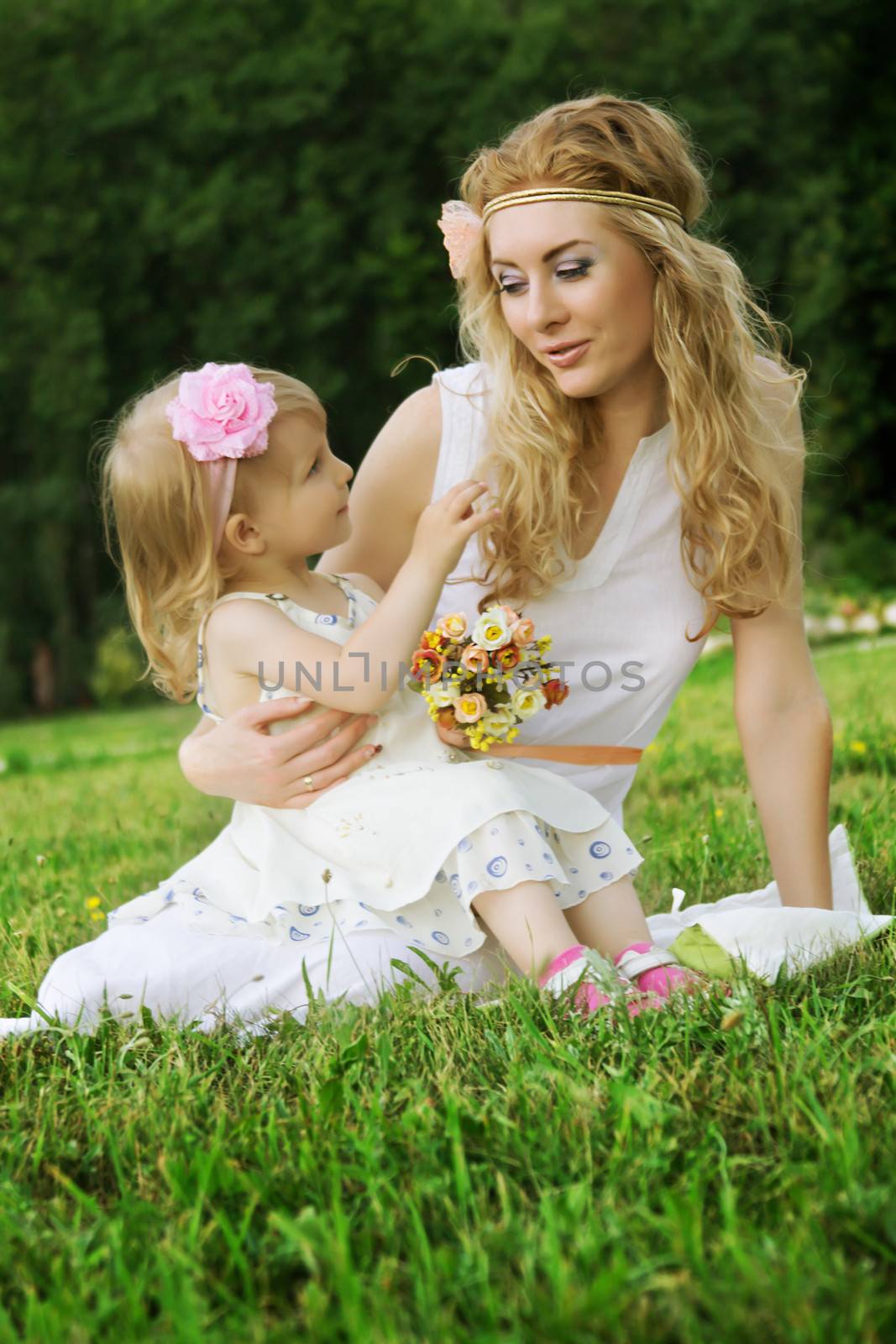 Romantic mother and smiling daughter sitting on grass